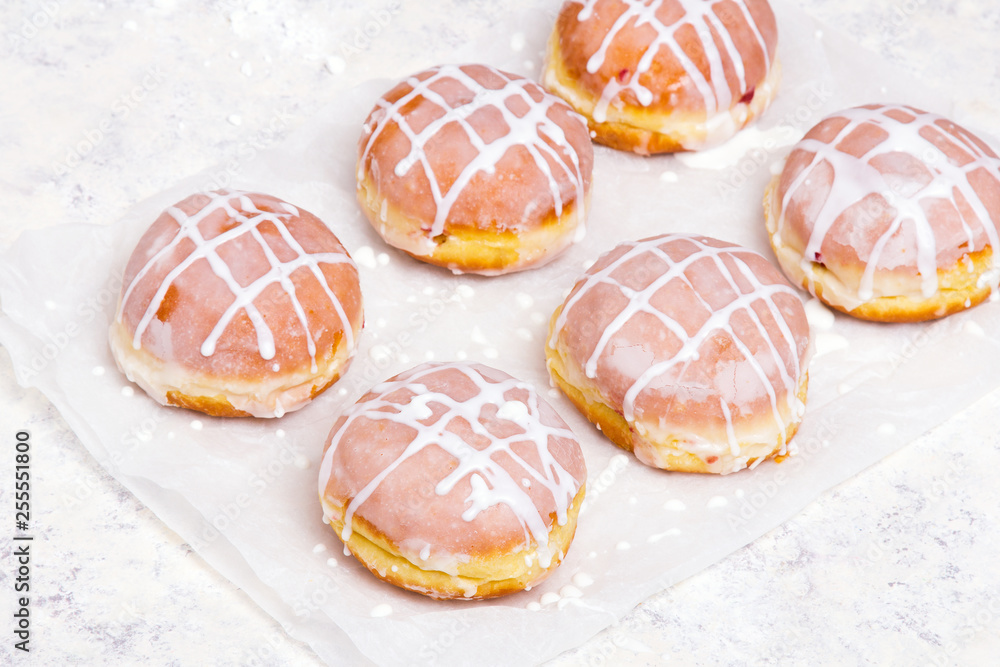 Traditional Polish donuts with white frosting on wooden background. Tasty doughnuts with jam.