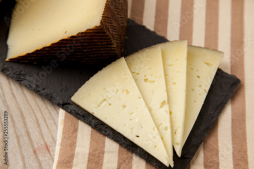 Lonchas  de queso curado español en un plato rectangular y de piedra