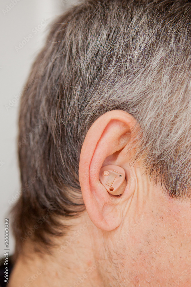 Obraz premium Close-up Digital modern hearing aid in the ear of aged old man