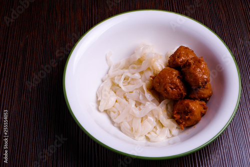 Kuey teow and meatballs in a white bowl on the table