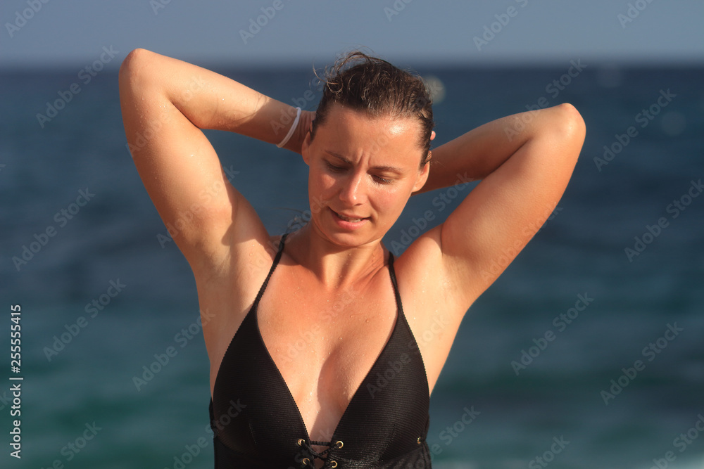 Wet young woman in swimwear come out from sea on beach after swim. Wet young woman in swimwear come out from sea on beach after swim.