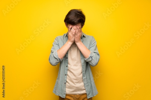 Teenager man over yellow wall with tired and sick expression © luismolinero
