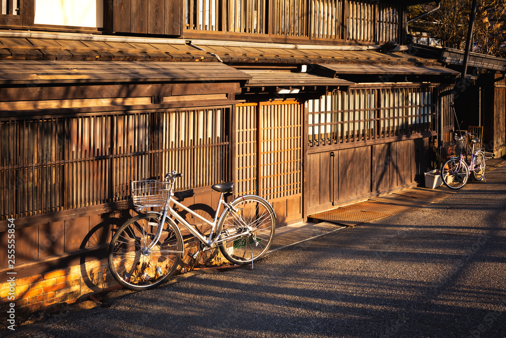 Old bicycle leaning against old wooden wall and home town in the japan