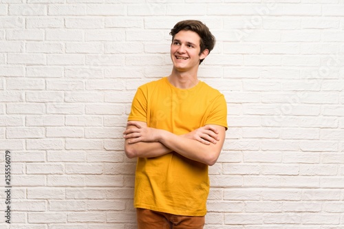 Teenager man over white brick wall Happy and smiling