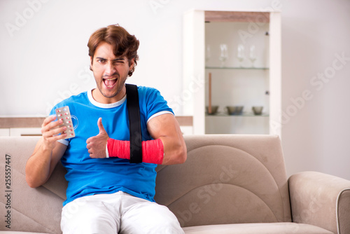Young man with injured arm sitting on the sofa  © Elnur