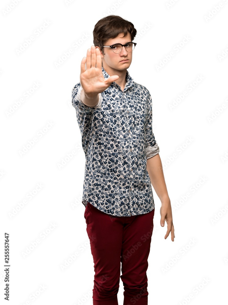 Teenager man with flower shirt and glasses making stop gesture denying a situation that thinks wrong over isolated white background Teenager man with flower shirt and glasses making stop gesture denying a situation that thinks wrong over isolated white background