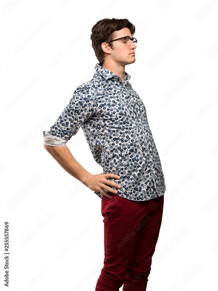 Teenager man with flower shirt and glasses suffering from backache for having made an effort over isolated white background Teenager man with flower shirt and glasses suffering from backache for having made an effort over isolated white background