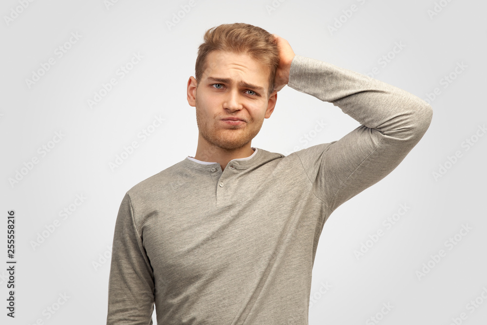 Attractive trendy young male freelancer with beard looking in camera with confused disappointed expression, scratching head. Handsome guy student remembers information for exam Attractive trendy young male freelancer with beard looking in camera with confused disappointed expression, scratching head. Handsome guy student remembers information for exam