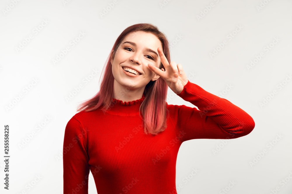 Portrait of young female showing two fingers peace. Copy space wall for your information or advertising content Portrait of young female showing two fingers peace. Copy space wall for your information or advertising content