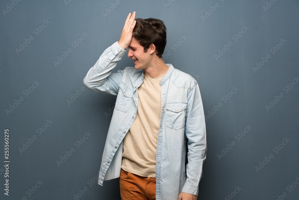 Teenager man with jean jacket over grey wall has realized something and intending the solution