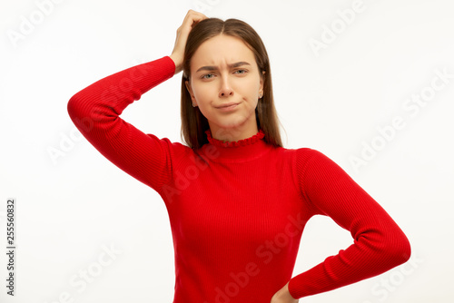 Attractive trendy young female freelancer looking away with confused disappointed expression, scratching head, on isolated white background. Handsome girl student not remembers information for exam © EverGrump