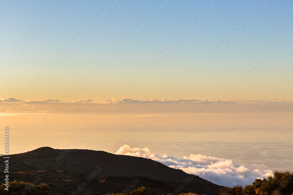 Clouds lie on the mountainside, calm ocean on the background