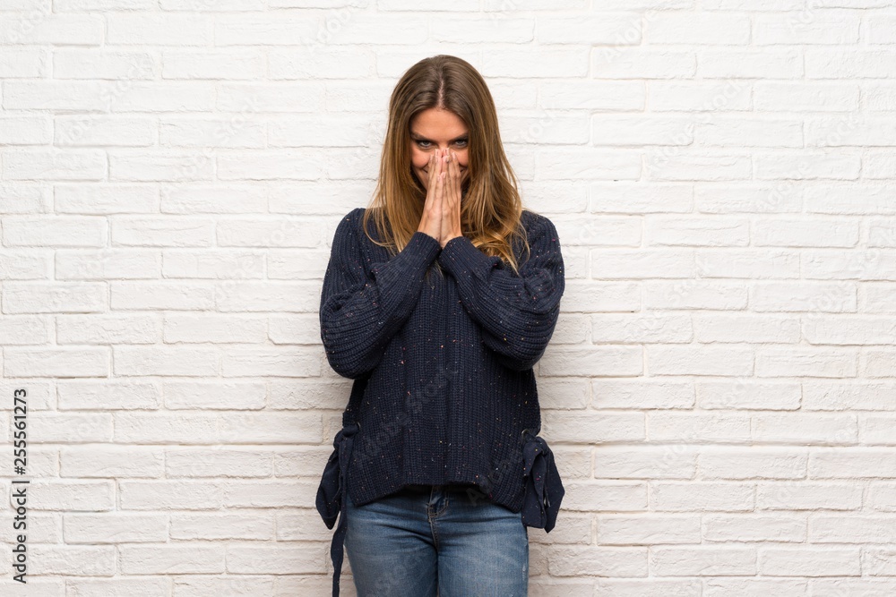 Blonde woman over brick wall pointing finger to the side Blonde woman over brick wall pointing finger to the side