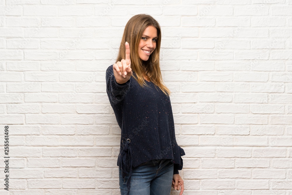 Blonde woman over brick wall showing and lifting a finger Blonde woman over brick wall showing and lifting a finger