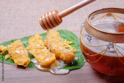 Honey dripping from wooden honey dipper and fried slices of the ripe BANANA also called Pisang Goreng, which are eaten as snack or used to accompany dishes in Malaysia