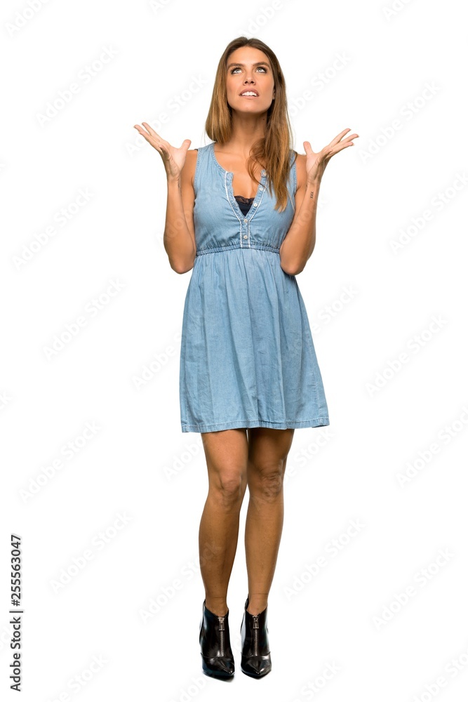 A full-length shot of a Blonde woman with jean dress frustrated by a bad situation over isolated white background A full-length shot of a Blonde woman with jean dress frustrated by a bad situation over isolated white background