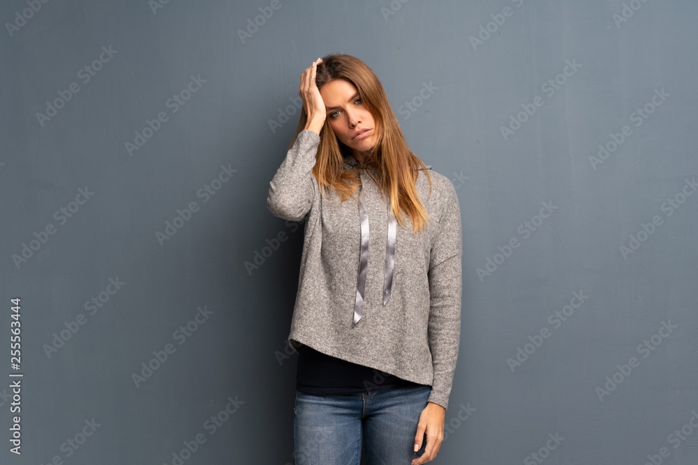 Blonde woman over grey background frustrated and takes hands on head Blonde woman over grey background frustrated and takes hands on head