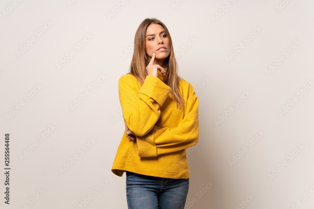 Woman with yellow sweater over isolated wall thinking an idea while looking up Woman with yellow sweater over isolated wall thinking an idea while looking up