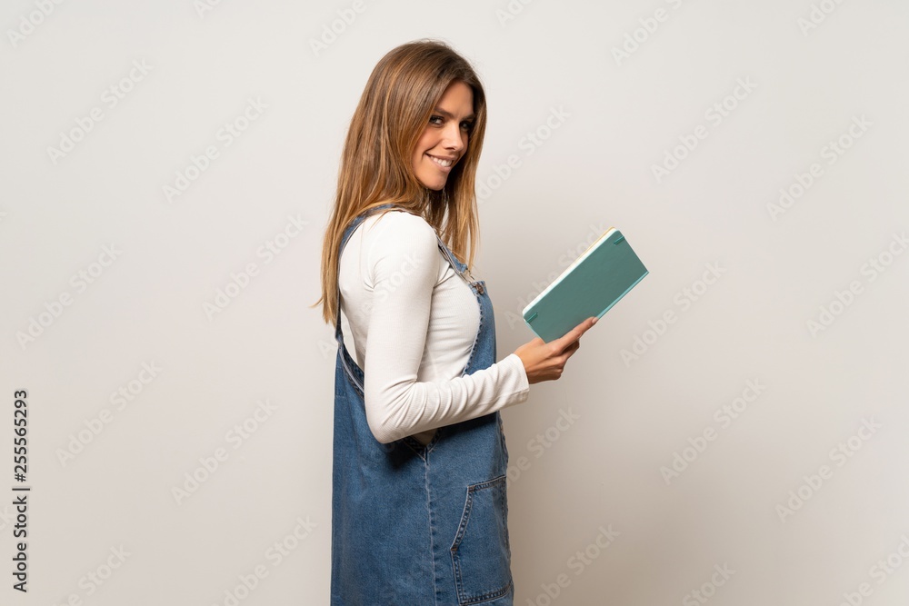 Beautiful woman over isolated white wall holding a book and enjoying reading Beautiful woman over isolated white wall holding a book and enjoying reading