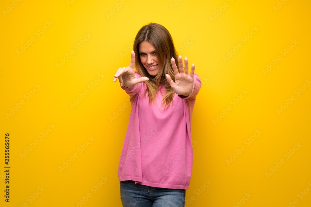 Woman with pink sweater over yellow wall counting seven with fingers Woman with pink sweater over yellow wall counting seven with fingers