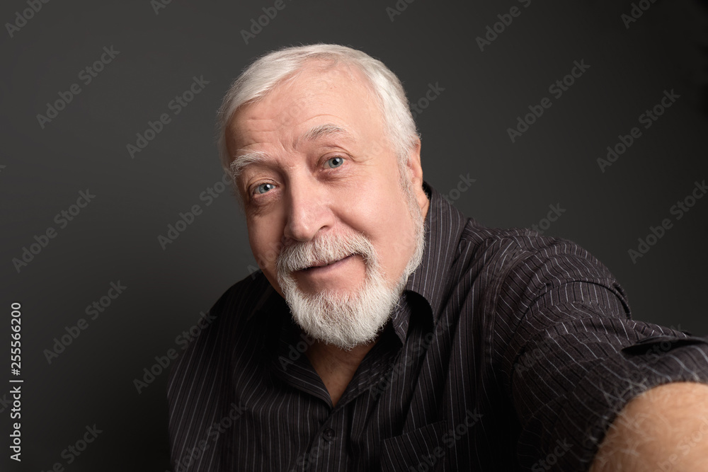 good-natured charismatic man on a gray background makes a selfie on the camera good-natured charismatic man on a gray background makes a selfie on the camera