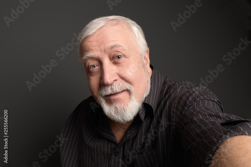 good-natured charismatic man on a gray background makes a selfie on the camera