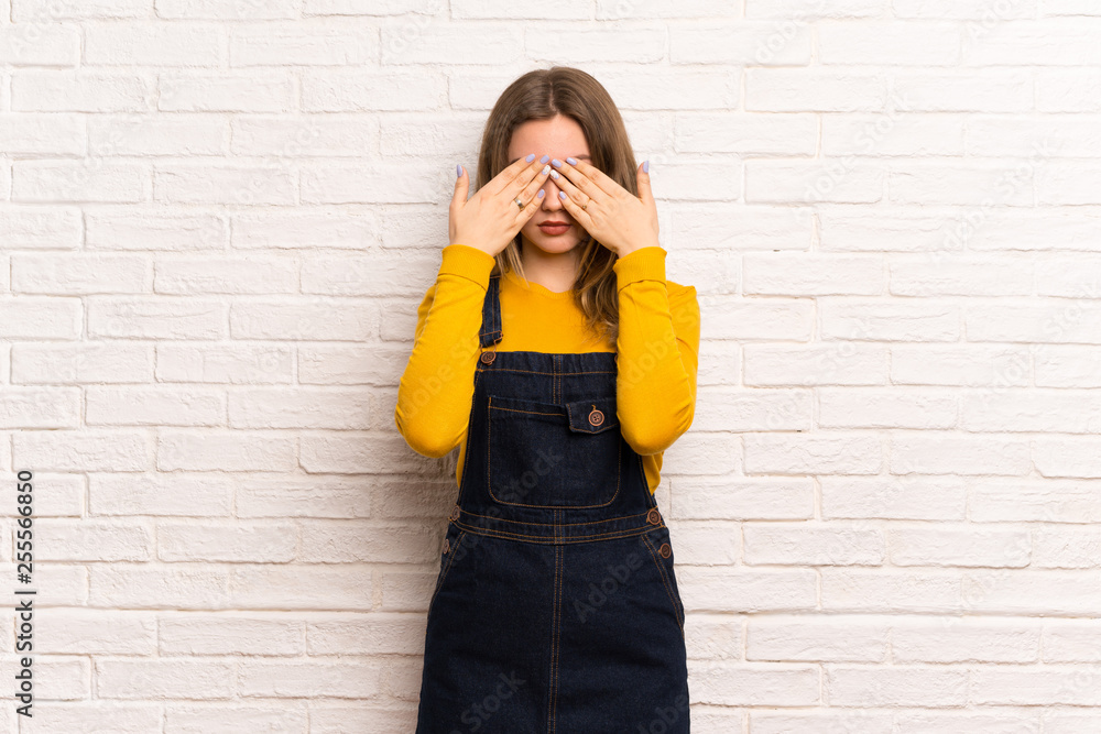 Teenager girl over white brick wall covering eyes by hands. Do not want to see something Teenager girl over white brick wall covering eyes by hands. Do not want to see something