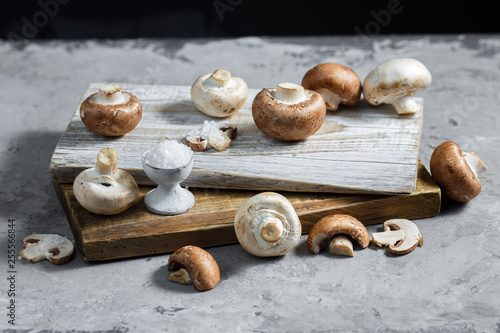 Composition with fresh champignon mushrooms on wooden board. Rustic style