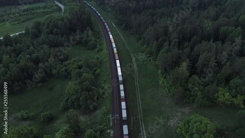 Aerial shot of cargo train running through the forests in the late evening