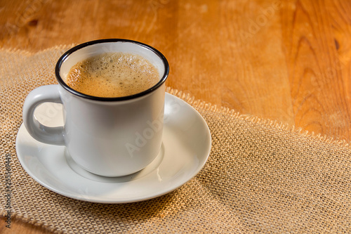 cup of coffee on jute canvas and wooden background © german