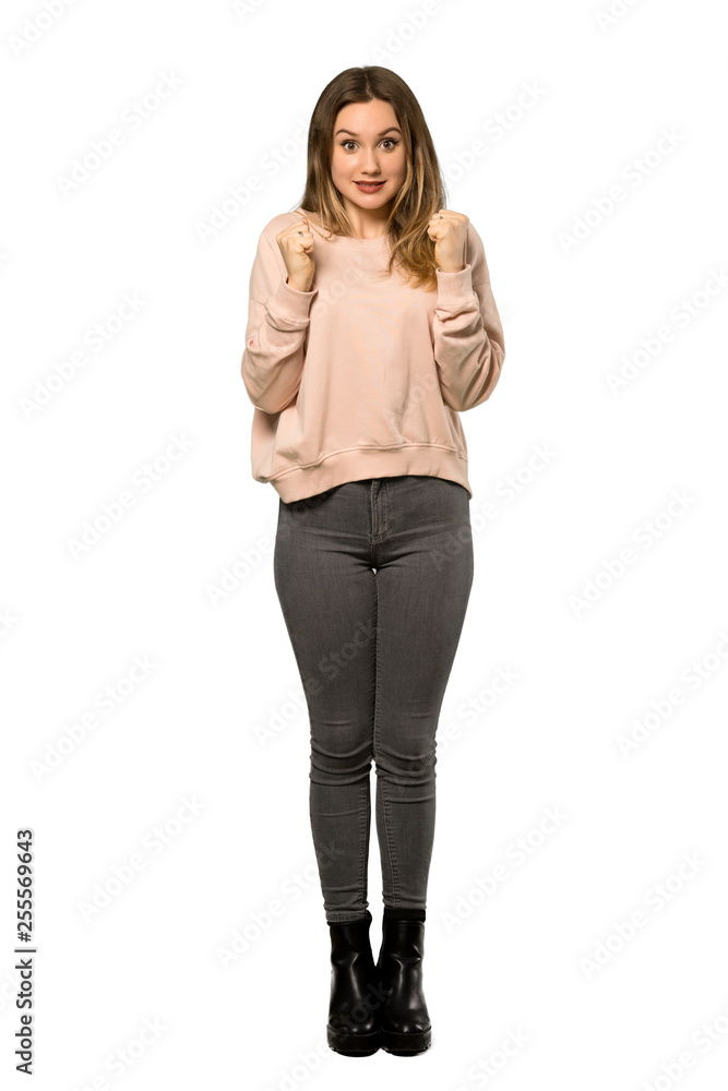 Fototapeta premium A full-length shot of a Teenager girl with pink sweater celebrating a victory in winner position over isolated white background