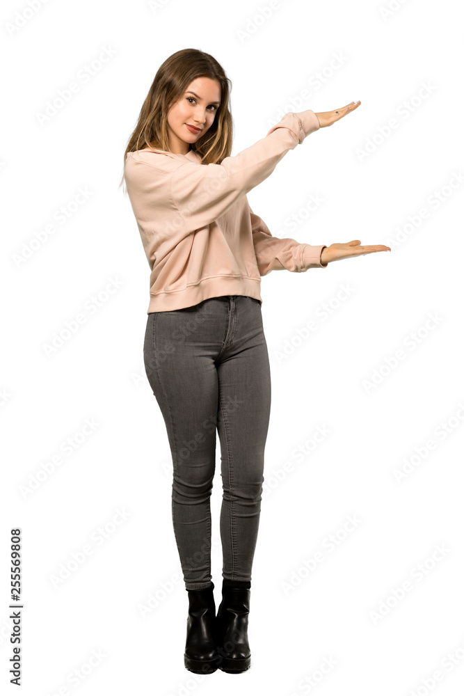 A full-length shot of a Teenager girl with pink sweater holding copyspace to insert an ad over isolated white background A full-length shot of a Teenager girl with pink sweater holding copyspace to insert an ad over isolated white background