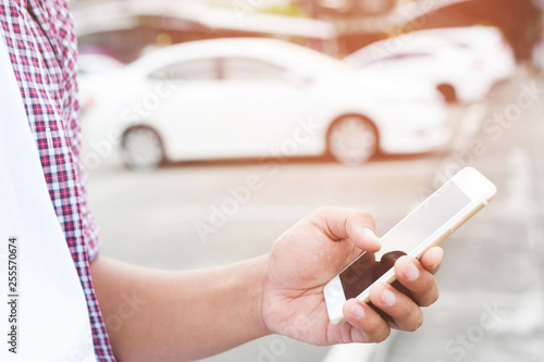 close up people man hand using a mobile smart phone call a car mechanic ask for help assistance because car broke in parking outdoor. standing wait beside broken car background. soft focus.