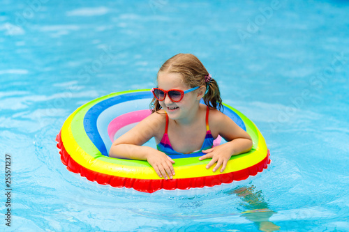 Child in swimming pool on toy ring. Kids swim.