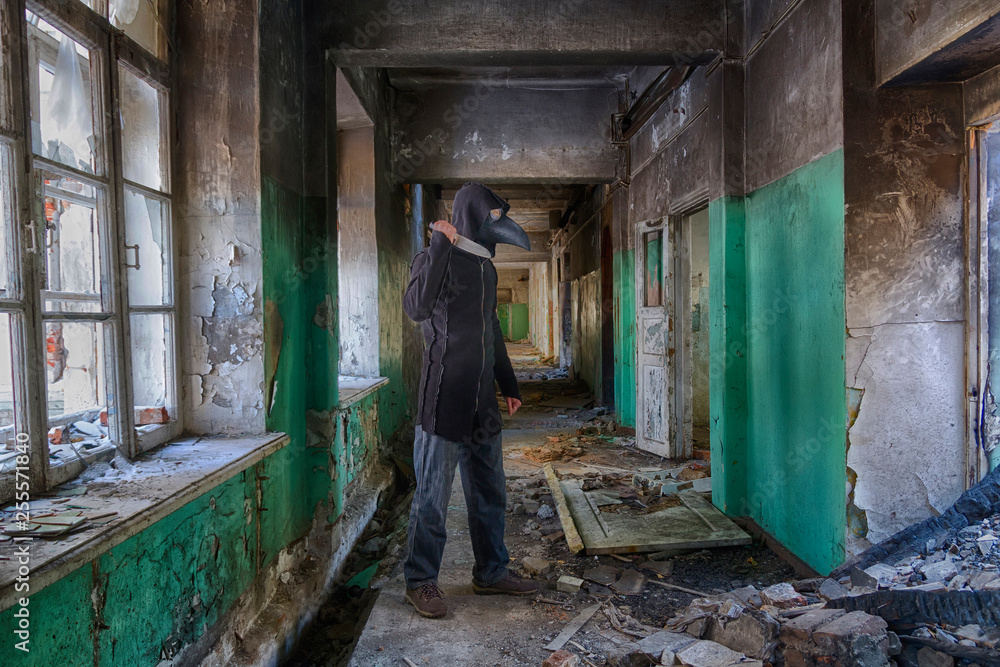Danger maniac with knife in hand, in leather mask of lague doctor and hood, inside old abandoned house Danger maniac with knife in hand, in leather mask of lague doctor and hood, inside old abandoned house