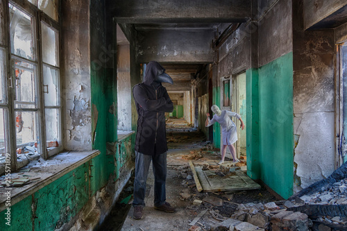 Tall man in plague doctor mask in hooded mantle and zombie monster nurse with knife. Horror movie scene in abandoned asylum or hospital © evgenzz