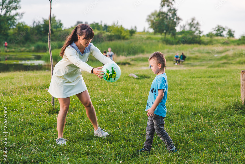 mother play with son in ball at green field.