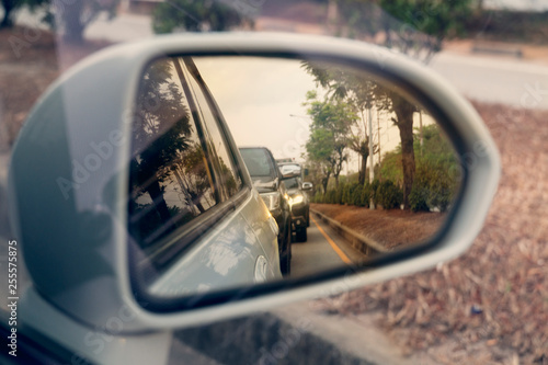 Cars run through the street from the White car's side view mirror. © thongchainak