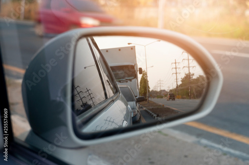 Cars run through the street from the White car's side view mirror. © thongchainak