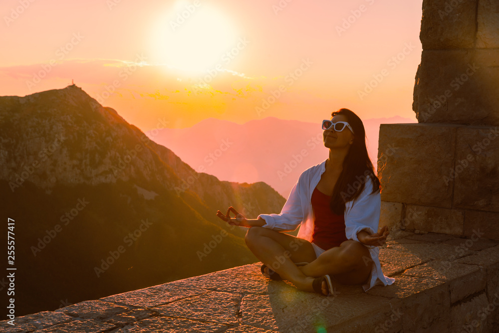 woman siting at the edge with beautiful view of sunset over mountains. summer vacation woman siting at the edge with beautiful view of sunset over mountains. summer vacation