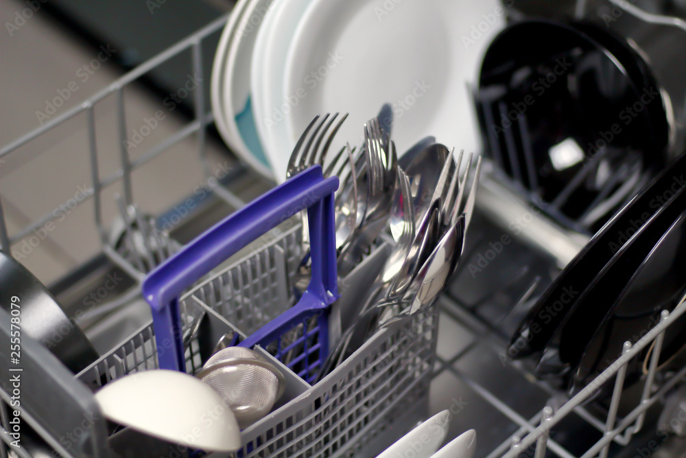 Dishwasher with white and black plates with bowls, forks, spoons