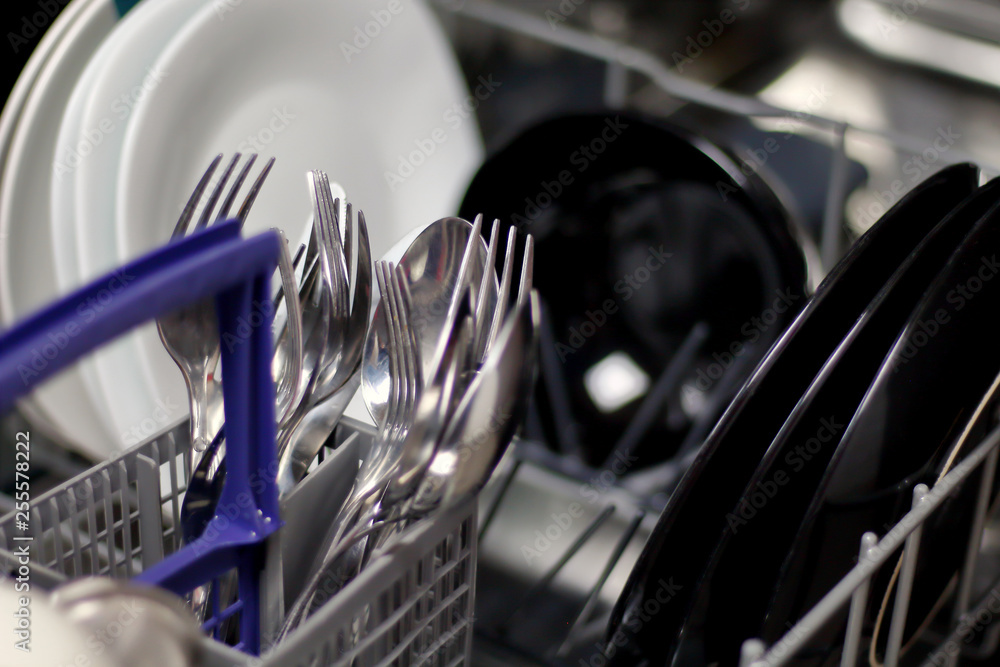 Dishwasher with white and black plates with bowls, forks, spoons