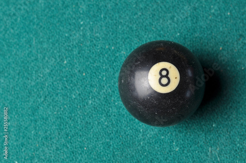 Old billiard ball number 8 black color on green billiard table, copy space