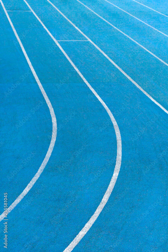 Fragment of blue synthetic surface of running tracks  of athletics stadium with white lines as texture, background