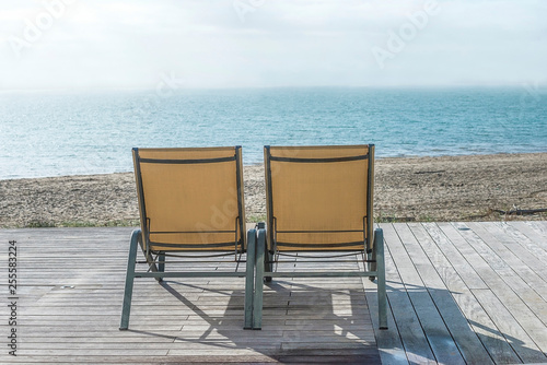 Beach holiday concept  two lounge chairs on the terrace in front of the blue sea
