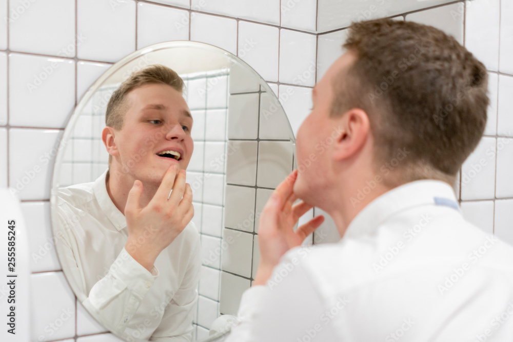 young businessman adjusting his look in front of mirror young businessman adjusting his look in front of mirror