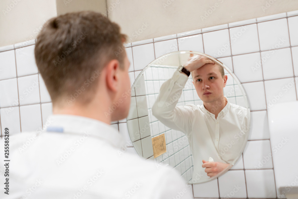 young businessman adjusting his look in front of mirror young businessman adjusting his look in front of mirror