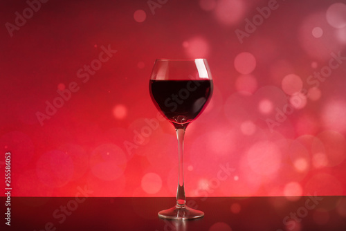 glass of wine on red background with bokeh