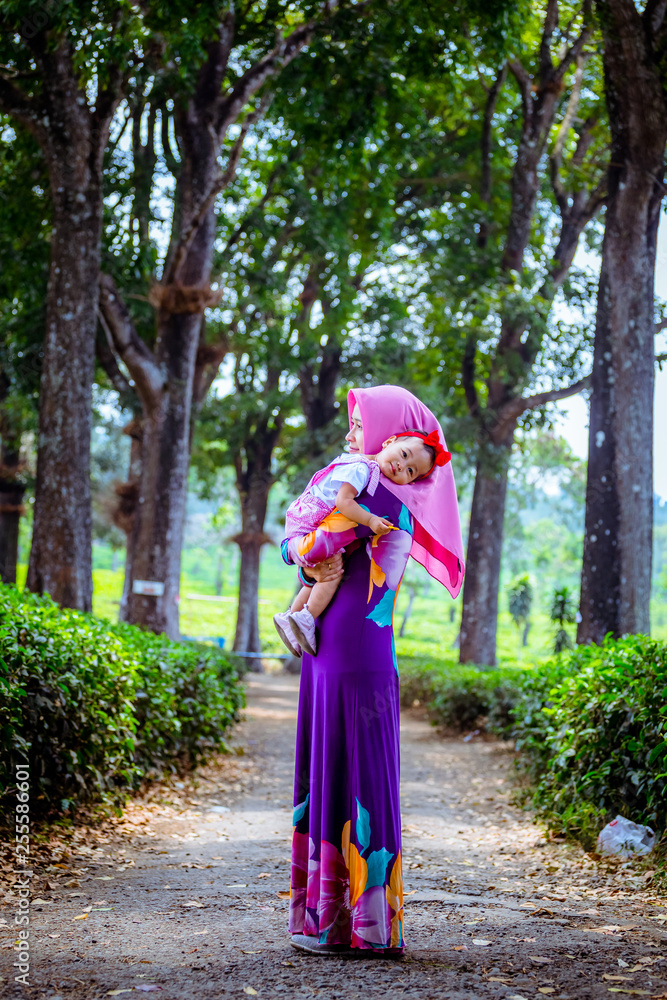 A happy Muslim mother with her daughter have fun at tea farm in Java Indonesia A happy Muslim mother with her daughter have fun at tea farm in Java Indonesia