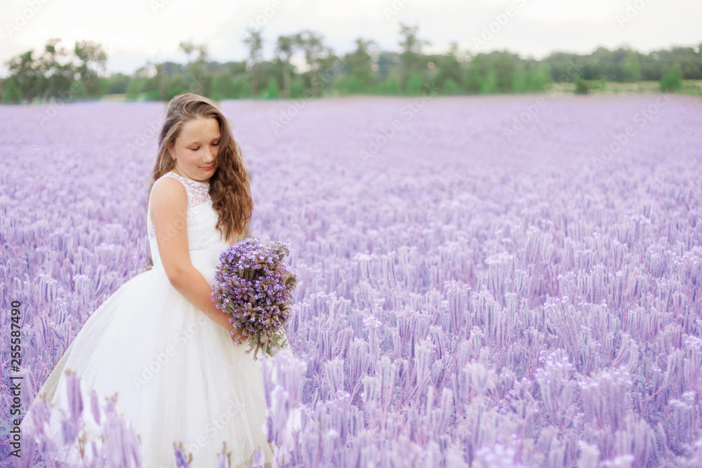 Beautiful little girl walks in the flowering field. Bouquet of violet flowers in the hands. Copy space. Beautiful little girl walks in the flowering field. Bouquet of violet flowers in the hands. Copy space.
